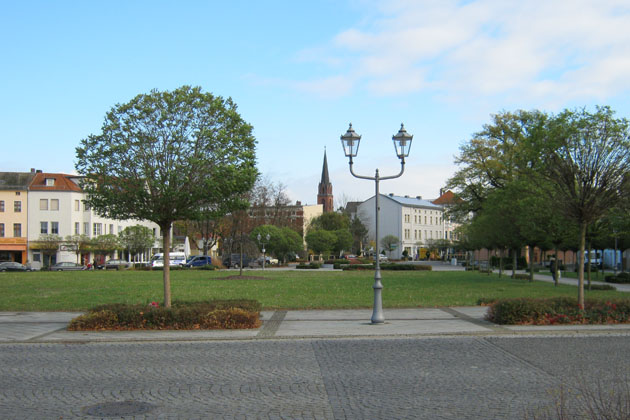 Blick über den Platz am Dreieck auf die Frankfurter Straße in Guben mit dem Kirchturm der Klosterkirche.