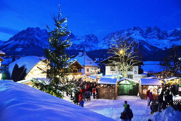 Der beschauliche Weihnachtsmarkt auf dem Goinger Kirchplatz wird umrahmt von der Kulisse des Wilden Kaisers in Tirol/Österreich.